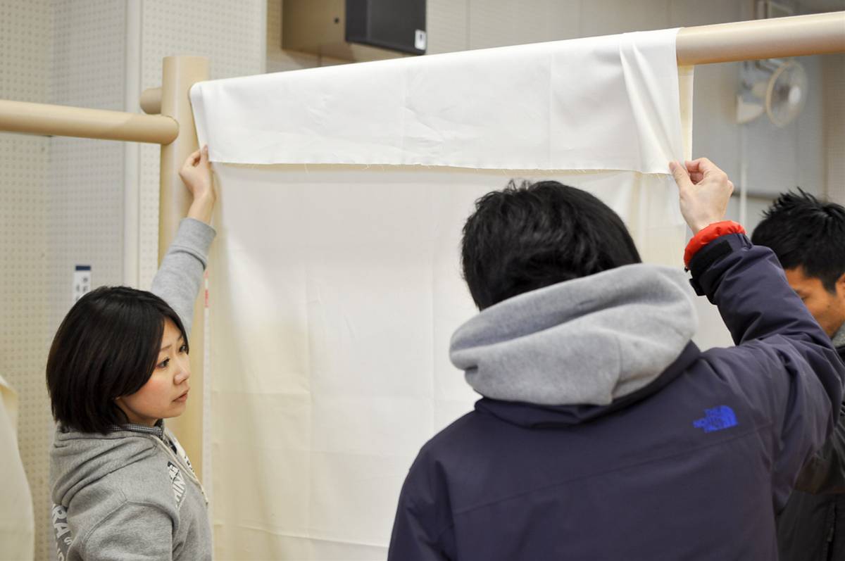 Workers setting up partition curtains at evacuation shelter