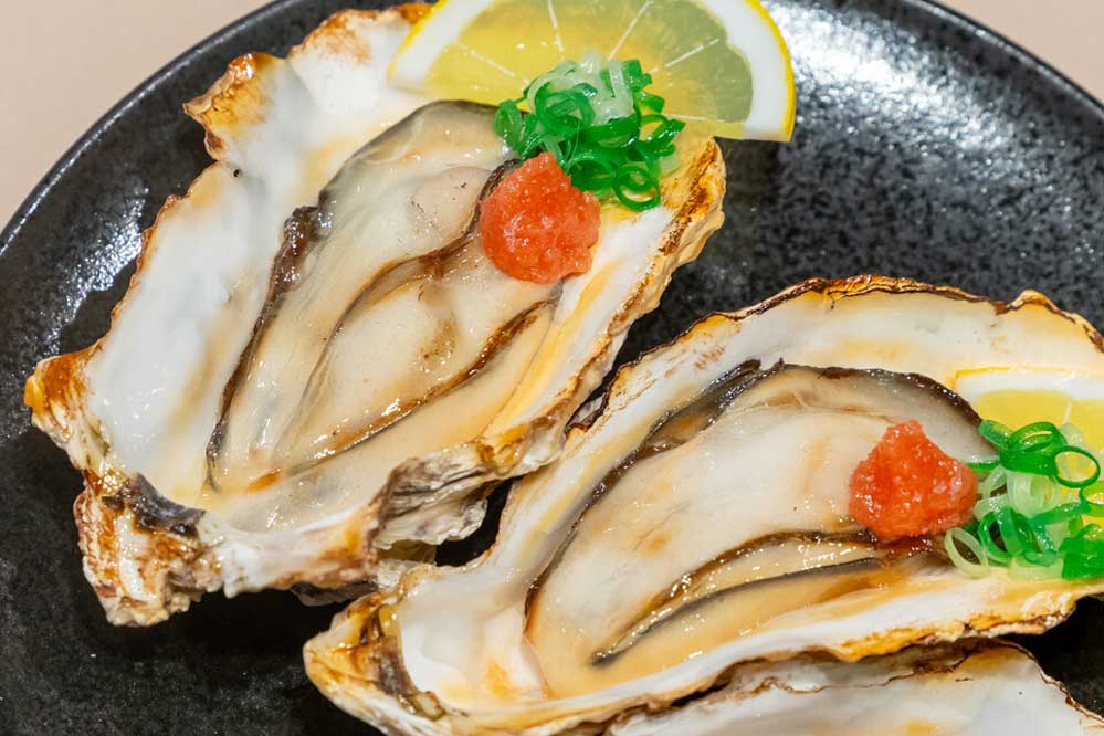Food replica of grilled oysters in shells with sliced lemons and scallions