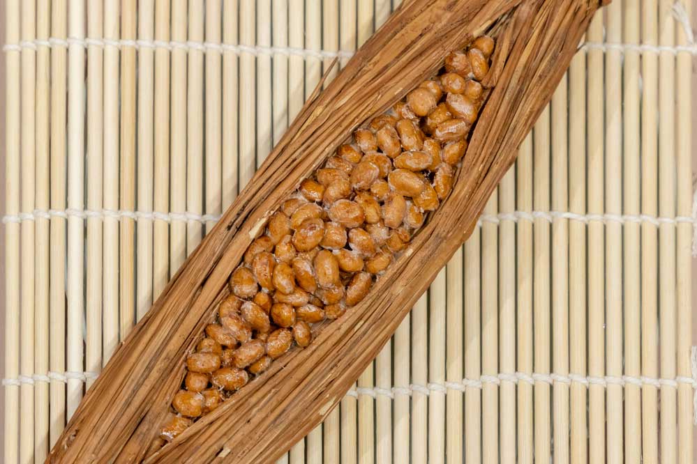 Food replica of nattō beans wrapped inside bundles of rice straw