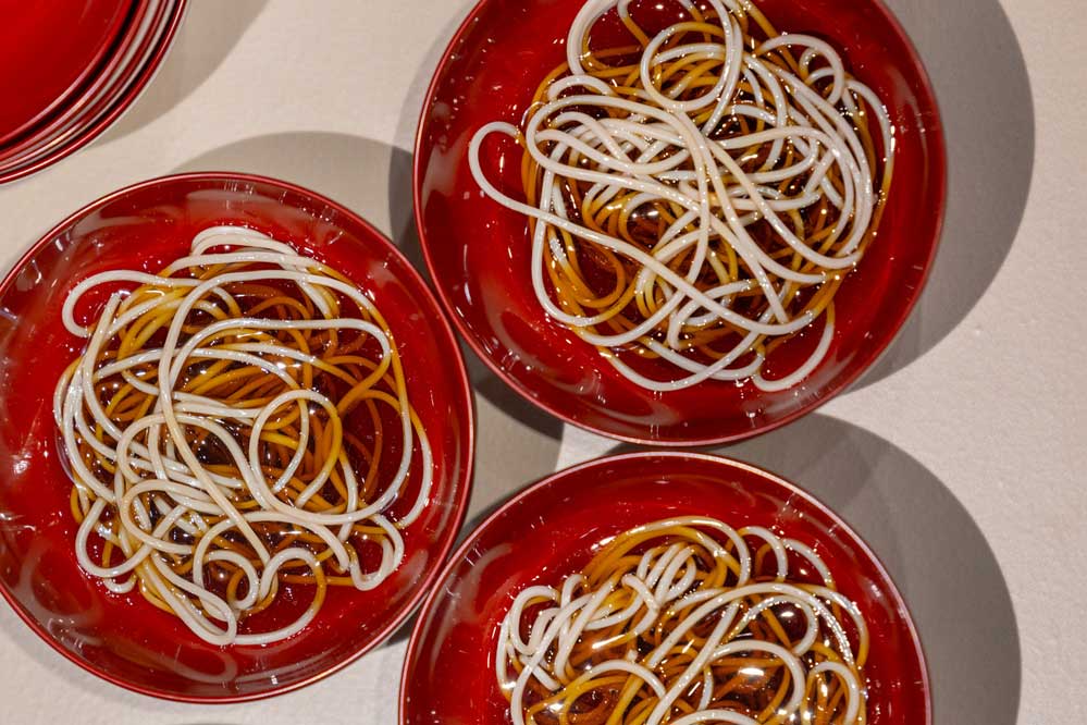 Food replica of wanko-soba noodles in red soup bowls
