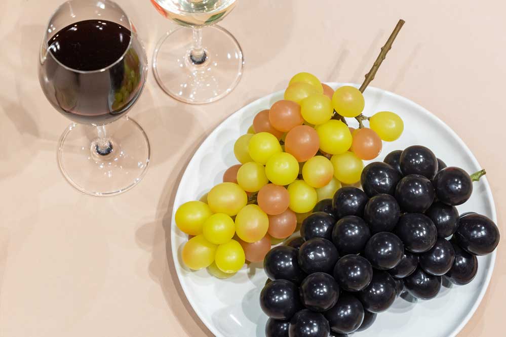 Replicas of Kōshū wine in wine glasses, and Japanese grapes on a white plate