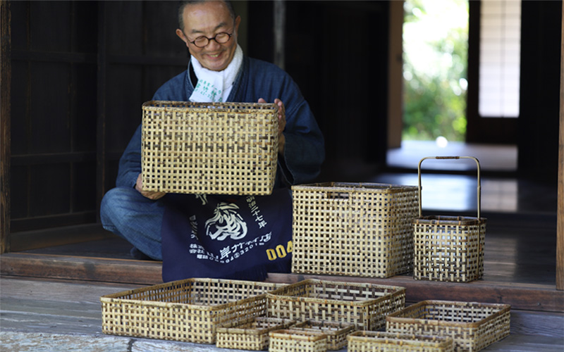 Yoshihiro Yamagishi sitting next to a stack of tiger bamboo baskets