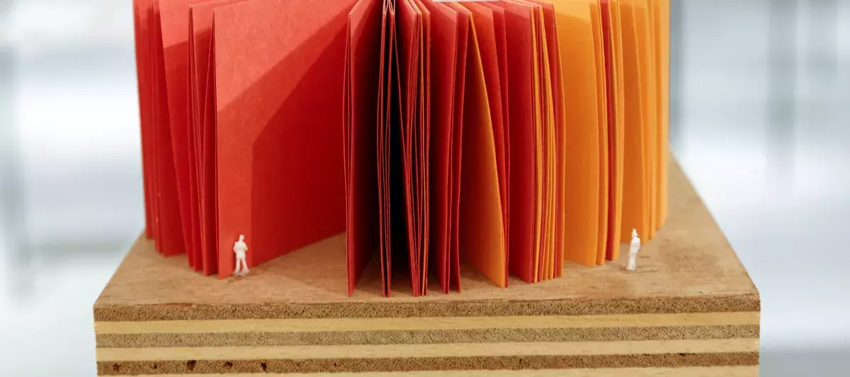 Smaller figures placed by a colorful paper booklet in the "Architecture is Everywhere" Series by Sou Fujimoto