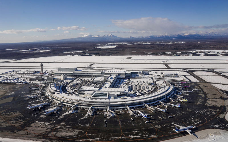 Shin Chitose Airport in Hokkaido blanketed in snow with a plane on the runway.