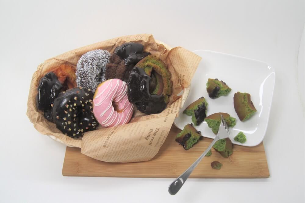 Lifelike plastic donuts in various flavors, part of fake food display.
