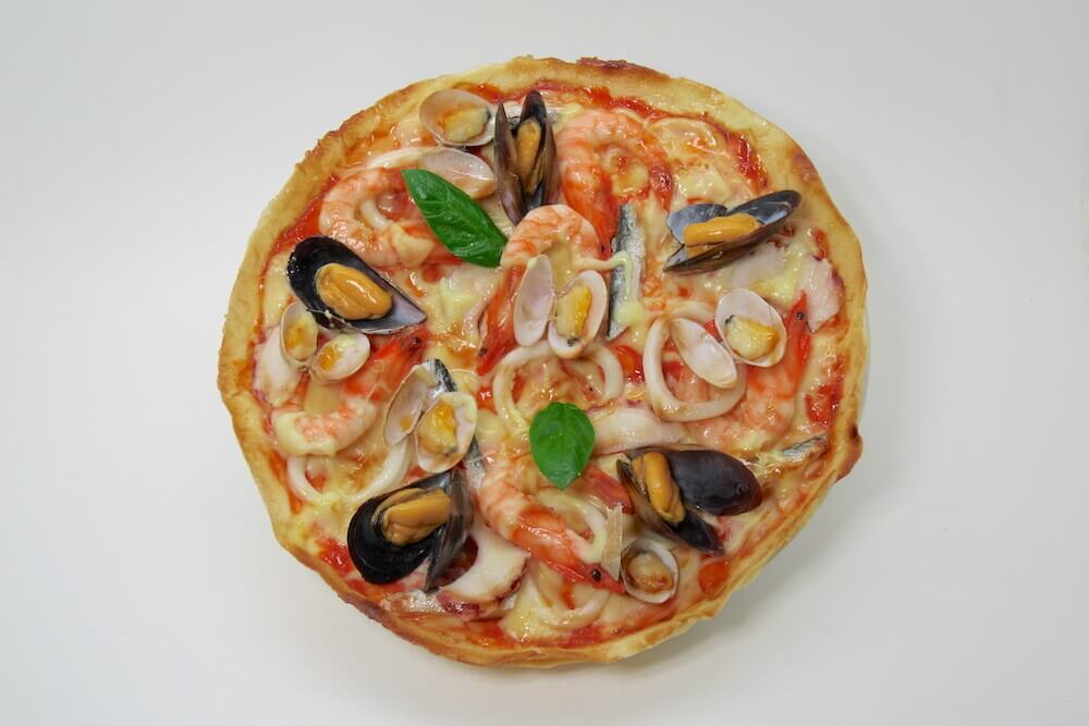 Plastic food model of a pizza slice with toppings.