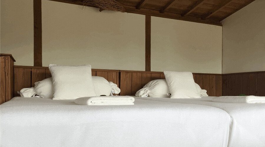 Minimalist Japanese-style bedroom with two beds, white bedding, and wooden accents.