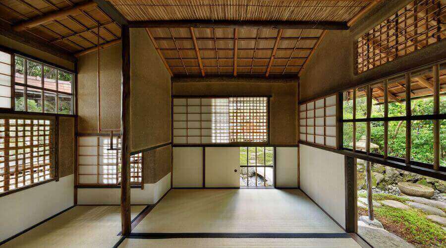 Japanese teahouse interior: tatami mats, shoji screens, numerous windows overlooking a serene garden.